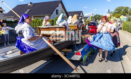 31. August 2025, Brandenburg, Burg (Spreewald): Auf einem Spreewaldkahn sitzend und daneben tanzend nehmen Frauen in Spreewaldtracht im Rahmen des lokalen und traditionellen Trachtenfestes an der Trachtenparade durch das Zentrum von Burger teil. Foto: Frank Hammerschmidt/dpa Stockfoto