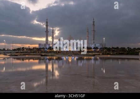 VAE - Abu Dhabi - Scheich Zayed große Moschee - Reflexionen der Dämmerung unter schweren Wolken über dem breiten marmorplatz Stockfoto