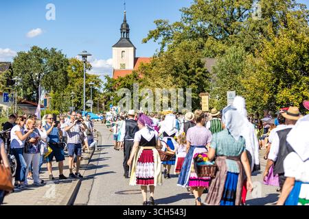 31. August 2025, Brandenburg, Burg (Spreewald): Die Menschen nehmen im Rahmen des Lokalgeschichte- und Trachtenfestes an der traditionellen Parade durch das Zentrum der Burg Teil und werden von Besuchern der Veranstaltung beobachtet. Foto: Frank Hammerschmidt/dpa Stockfoto