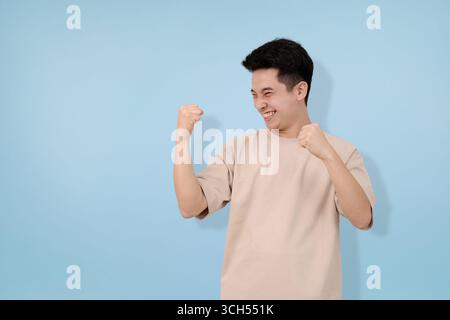 Der aufgeregte Mann-Ausdruck feiert mit geschlossenen Fäusten in freudiger Euphorie Stockfoto