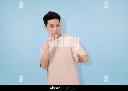 Junger Mann mit Gesten im Studio im blauen Hintergrund Stockfoto