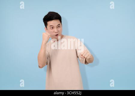 Junger Mann mit Gesten im Studio im blauen Hintergrund Stockfoto