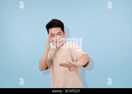 Junger Mann mit Gesten im Studio im blauen Hintergrund Stockfoto