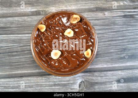 Schokoladencreme mit Kuchen, gekrönt mit Schokoladenpaste und Haselnussstücken und mit Kuchen überzogen, ein weiches, zubereitetes Essen mit Schichten geschlagener Crea Stockfoto