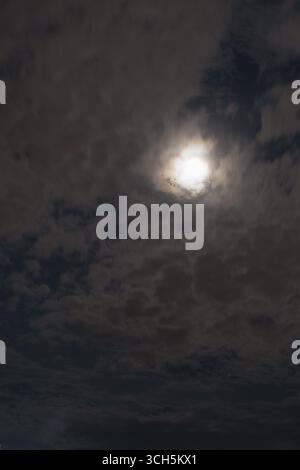 Das Mondlicht scheint hell durch die Wolken am Nachthimmel. Stockfoto