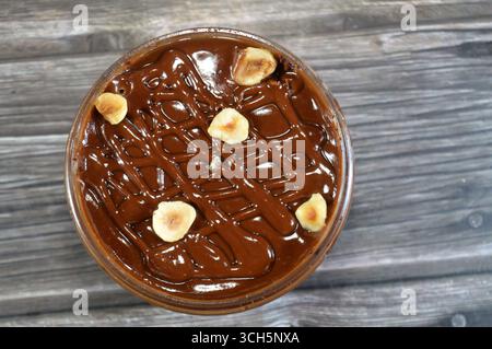Schokoladencreme mit Kuchen, gekrönt mit Schokoladenpaste und Haselnussstücken und mit Kuchen überzogen, ein weiches, zubereitetes Essen mit Schichten geschlagener Crea Stockfoto