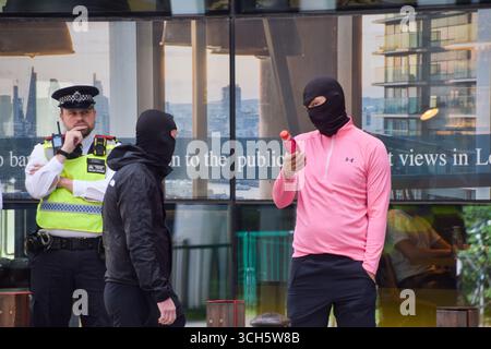 London, England, Großbritannien. 31. August 2025. Ein Polizeibeamter beobachtet maskierte Anti-Migranten-Gegenprotestierende, während sich Demonstranten zur Unterstützung von Migranten vor dem Britannia International Hotel in Canary Wharf versammeln, wo Asylsuchende untergebracht sind, Teil der laufenden Demonstrationen im Zusammenhang mit Migranten, die in ganz Großbritannien stattfinden. (Kreditbild: © Vuk Valcic/ZUMA Press Wire) NUR REDAKTIONELLE VERWENDUNG! Nicht für kommerzielle ZWECKE! Stockfoto