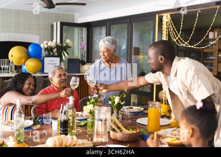 Zu Hause feiern, generationenübergreifende Familien mit Freude und Lachen anstoßen Stockfoto