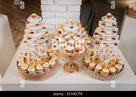 Luxuriöser Hochzeitstisch mit Cupcakes, Macarons und cremigen Mini-Leckereien Stockfoto