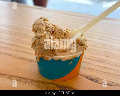 Portion Eis mit Kaffeegeschmack in einer Tasse. Kaltes Dessert mit Plastiklöffel Stockfoto