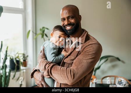 Porträt eines glücklichen Vaters, der den Sohn zu Hause umschließt Stockfoto
