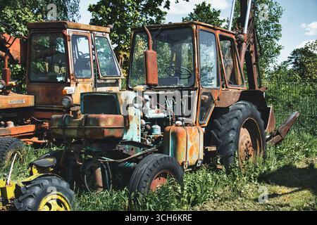Rostiger blauer Traktor in verwachsenem Gras mit ländlicher Verfallsszene Stockfoto