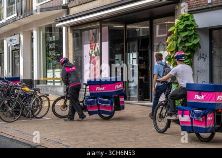 Radfahren im Stadtzentrum von Groningen, Altstadt, Zweigstelle des Lebensmittellieferdienstes Flink, Niederlande, Stockfoto