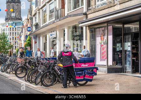 Radfahren im Stadtzentrum von Groningen, Altstadt, Zweigstelle des Lebensmittellieferdienstes Flink, Niederlande, Stockfoto