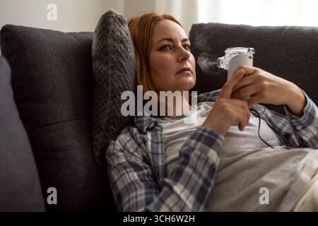 Aerosol für Vernebler. Frau mittleren Alters mit Inhalator Maschine, saisonale Grippe Stockfoto