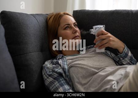 Aerosol für Vernebler. Frau mittleren Alters mit Inhalator Maschine, saisonale Grippe Stockfoto