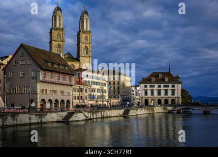 Stadtlandschaft mit klassischen Gebäuden an der Limmat in der Altstadt und dem berühmten romanischen Dom Grossmunster mit zwei Türmen, Zürich, Schweiz Stockfoto