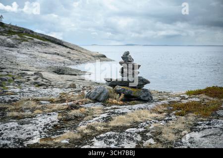 Ausgeglichener Steinhaufen auf zerklüfteter Küstenlandschaft unter bewölktem Himmel im Weißen Meer, Natur von Karelien. Stockfoto