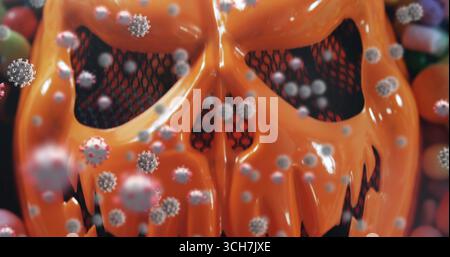 Bild einer orangefarbenen halloween-Maske mit mehreren schwebenden Zellen und Süßigkeiten im Hintergrund Stockfoto