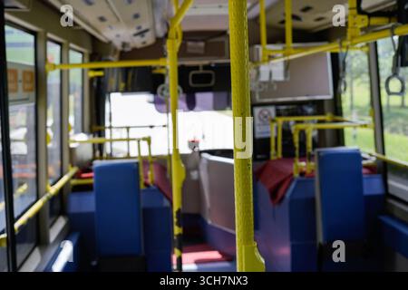 In einem öffentlichen Bus mit hellgelben Pfählen, blauen Sitzen und einem Gang für Pendler Stockfoto