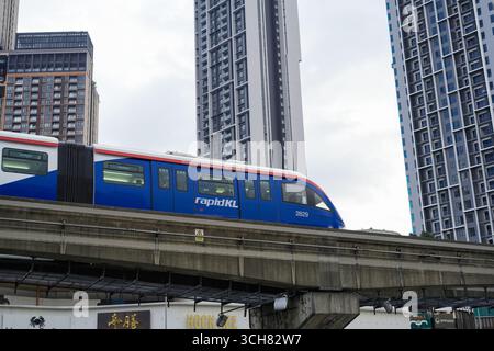 16. September 2025 Ein eleganter Wolkenkratzer erhebt sich neben einer erhöhten Eisenbahnlinie, als ein blau-weißer RapidKL-Zug vorbeifährt und in Kuala Lumpur Malaysia erschossen wurde Stockfoto