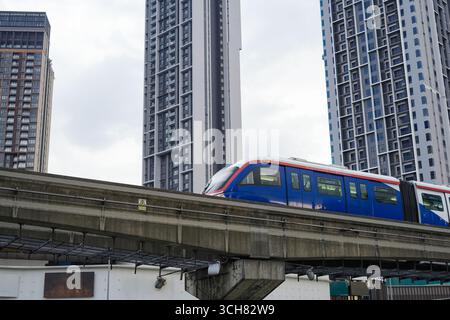 16. September 2025 Ein eleganter Wolkenkratzer erhebt sich neben einer erhöhten Eisenbahnlinie, als ein blau-weißer RapidKL-Zug vorbeifährt und in Kuala Lumpur Malaysia erschossen wurde Stockfoto