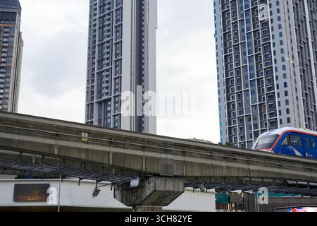 16. September 2025 Ein eleganter Wolkenkratzer erhebt sich neben einer erhöhten Eisenbahnlinie, als ein blau-weißer RapidKL-Zug vorbeifährt und in Kuala Lumpur Malaysia erschossen wurde Stockfoto
