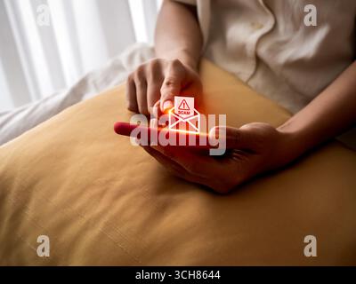 Person, die ein Smartphone mit einem leuchtenden E-Mail-Symbol für Betrug hält, stellt SMS-Benachrichtigungen, Betrugsnachrichten, Phishing-Angriffe, Online-Sicherheitsrisiken und digitale Sicherheit dar Stockfoto