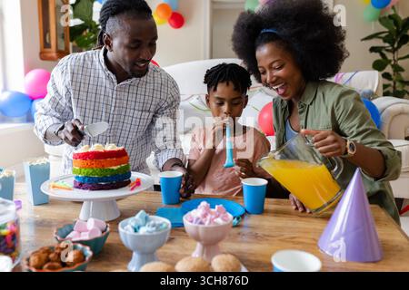 Auf Party, Geburtstag zu Hause, Kind bläst Partyhorn, Eltern servieren Getränke Stockfoto
