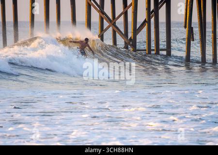 Amelia Island Surfer am Amelia by the Sea Pier, der auf einer großen Welle durch Hurrikan Erin Hunderte von Meilen vor der Küste im Nordosten Floridas reitet. Stockfoto