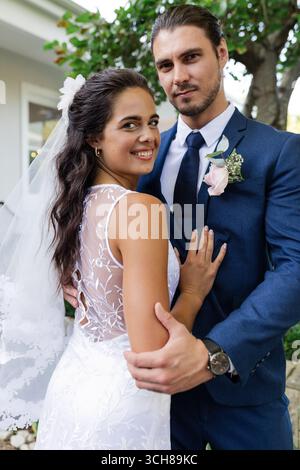 Lächelnde Braut und Bräutigam, die im Freien ihren besonderen Hochzeitstag feiern Stockfoto
