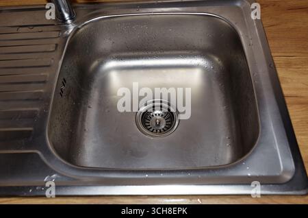 Wasserabfluss auf das Spülbecken aus Edelstahl. Kanalisation von oben im Waschbecken. Küche Unterbau Edelstahl Waschbecken Stockfoto
