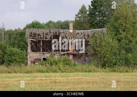 Ein altes hölzernes Bauernhaus steht in Estlands herbstlicher Landschaft vergessen Stockfoto