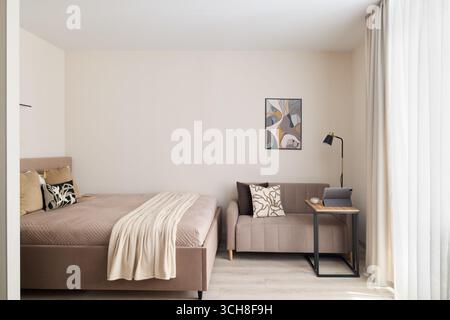 Ein stilvolles, modernes, minimalistisches Schlafzimmer mit gemütlichem Sitzbereich für Entspannung und Komfort Stockfoto
