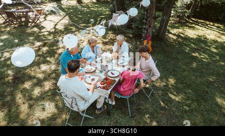 Luftaufnahme von Familientreffen zum Grillen im Sommergarten, Reden und Essen gegrillter Speisen. Stockfoto