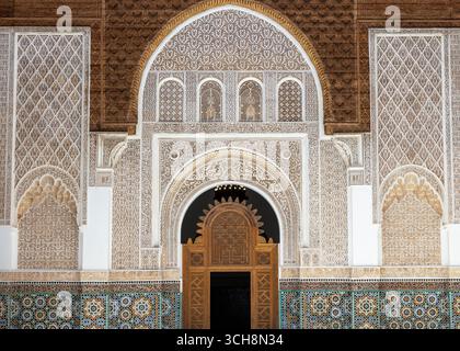 Geschnitzter Stuck und Zedernholzfries mit arabischer Kalligraphie und kleinen Bogenfenstern an der Hofwand von Ben Youssef Madrasa (Medersa Ben Youssef) Stockfoto