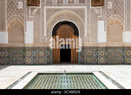 Geschnitzter Stuck und Zedernholzfries mit arabischer Kalligraphie und kleinen Bogenfenstern an der Hofwand von Ben Youssef Madrasa (Medersa Ben Youssef) Stockfoto