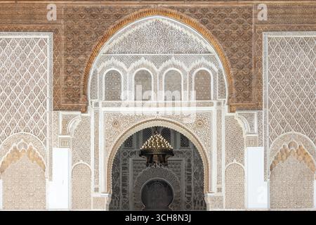 Geschnitzter Stuck und Zedernholzfries mit arabischer Kalligraphie und kleinen Bogenfenstern an der Hofwand von Ben Youssef Madrasa (Medersa Ben Youssef) Stockfoto