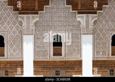 Geschnitzter Stuck und Zedernholzfries mit arabischer Kalligraphie und kleinen Bogenfenstern an der Hofwand von Ben Youssef Madrasa (Medersa Ben Youssef) Stockfoto