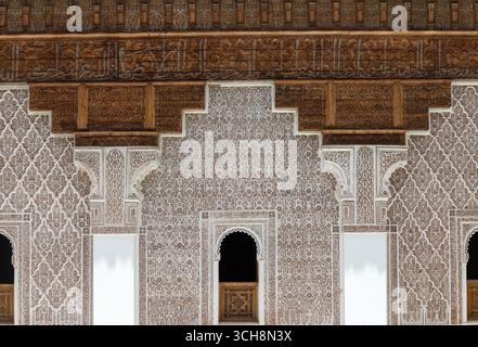 Geschnitzter Stuck und Zedernholzfries mit arabischer Kalligraphie und kleinen Bogenfenstern an der Hofwand von Ben Youssef Madrasa (Medersa Ben Youssef) Stockfoto