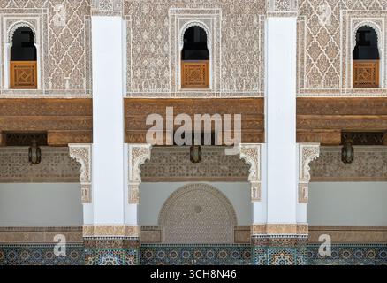 Geschnitzter Stuck und Zedernholzfries mit arabischer Kalligraphie und kleinen Bogenfenstern an der Hofwand von Ben Youssef Madrasa (Medersa Ben Youssef) Stockfoto