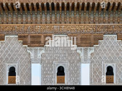 Geschnitzter Stuck und Zedernholzfries mit arabischer Kalligraphie und kleinen Bogenfenstern an der Hofwand von Ben Youssef Madrasa (Medersa Ben Youssef) Stockfoto