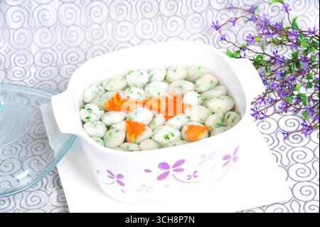 Schnittlauch-infundierte Jakobsbällchen in klarer Bouillon Stockfoto
