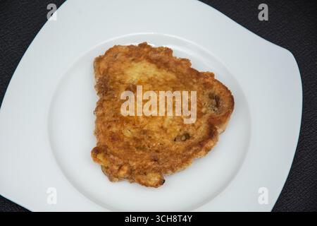 Das Bild zeigt ein Stück paniertes und frittiertes Fleisch, das allgemein als Schnitzel oder paniertes Schnitzel bekannt ist. Schnitzel ist eine Schüssel aus dünnem, knochenlosem Ich Stockfoto
