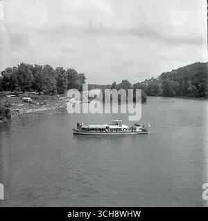Eine dynamische Szene des Flusslebens am Sewerski Donets in Swiatohirsk in den 1970er-80er Jahren Der Rahmen zeigt verschiedene Schiffe, von Freizeitbooten und Flussbahnen voller Touristen bis hin zu schnellen Motorbooten, die sich vor der berühmten Landschaft der Heiligen Berge Lavra und Kreidehügel befinden. Das Foto vermittelt die Atmosphäre eines beliebten sowjetischen Resorts und ist ein anschauliches Zeugnis für den entwickelten Wassertourismus. Es ist ein nostalgisches Bild eines aktiven Sommerurlaubs und ein Symbol für das friedliche, unbeschwerte Leben im Donbass vor dem Krieg Stockfoto