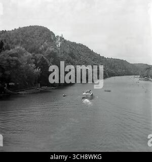 Eine dynamische Szene des Flusslebens am Sewerski Donets in Swiatohirsk in den 1970er-80er Jahren Der Rahmen zeigt verschiedene Schiffe, von Freizeitbooten und Flussbahnen voller Touristen bis hin zu schnellen Motorbooten, die sich vor der berühmten Landschaft der Heiligen Berge Lavra und Kreidehügel befinden. Das Foto vermittelt die Atmosphäre eines beliebten sowjetischen Resorts und ist ein anschauliches Zeugnis für den entwickelten Wassertourismus. Es ist ein nostalgisches Bild eines aktiven Sommerurlaubs und ein Symbol für das friedliche, unbeschwerte Leben im Donbass vor dem Krieg Stockfoto