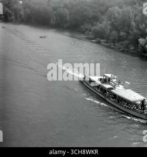 Eine dynamische Szene des Flusslebens am Sewerski Donets in Swiatohirsk in den 1970er-80er Jahren Der Rahmen zeigt verschiedene Schiffe, von Freizeitbooten und Flussbahnen voller Touristen bis hin zu schnellen Motorbooten, die sich vor der berühmten Landschaft der Heiligen Berge Lavra und Kreidehügel befinden. Das Foto vermittelt die Atmosphäre eines beliebten sowjetischen Resorts und ist ein anschauliches Zeugnis für den entwickelten Wassertourismus. Es ist ein nostalgisches Bild eines aktiven Sommerurlaubs und ein Symbol für das friedliche, unbeschwerte Leben im Donbass vor dem Krieg Stockfoto