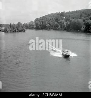 Eine dynamische Szene des Flusslebens am Sewerski Donets in Swiatohirsk in den 1970er-80er Jahren Der Rahmen zeigt verschiedene Schiffe, von Freizeitbooten und Flussbahnen voller Touristen bis hin zu schnellen Motorbooten, die sich vor der berühmten Landschaft der Heiligen Berge Lavra und Kreidehügel befinden. Das Foto vermittelt die Atmosphäre eines beliebten sowjetischen Resorts und ist ein anschauliches Zeugnis für den entwickelten Wassertourismus. Es ist ein nostalgisches Bild eines aktiven Sommerurlaubs und ein Symbol für das friedliche, unbeschwerte Leben im Donbass vor dem Krieg Stockfoto