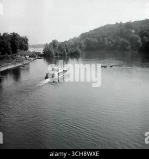 Eine dynamische Szene des Flusslebens am Sewerski Donets in Swiatohirsk in den 1970er-80er Jahren Der Rahmen zeigt verschiedene Schiffe, von Freizeitbooten und Flussbahnen voller Touristen bis hin zu schnellen Motorbooten, die sich vor der berühmten Landschaft der Heiligen Berge Lavra und Kreidehügel befinden. Das Foto vermittelt die Atmosphäre eines beliebten sowjetischen Resorts und ist ein anschauliches Zeugnis für den entwickelten Wassertourismus. Es ist ein nostalgisches Bild eines aktiven Sommerurlaubs und ein Symbol für das friedliche, unbeschwerte Leben im Donbass vor dem Krieg Stockfoto