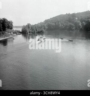 Eine dynamische Szene des Flusslebens am Sewerski Donets in Swiatohirsk in den 1970er-80er Jahren Der Rahmen zeigt verschiedene Schiffe, von Freizeitbooten und Flussbahnen voller Touristen bis hin zu schnellen Motorbooten, die sich vor der berühmten Landschaft der Heiligen Berge Lavra und Kreidehügel befinden. Das Foto vermittelt die Atmosphäre eines beliebten sowjetischen Resorts und ist ein anschauliches Zeugnis für den entwickelten Wassertourismus. Es ist ein nostalgisches Bild eines aktiven Sommerurlaubs und ein Symbol für das friedliche, unbeschwerte Leben im Donbass vor dem Krieg Stockfoto